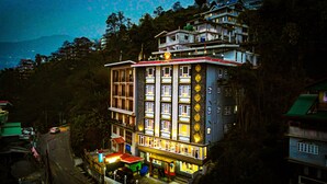A multi-story hotel with balconies, a ground-level restaurant, and a view of the surrounding area. - Rufina Pinasa Residency (Gangtok)