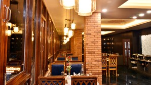 A restaurant with wooden furniture, hanging light fixtures, and brick walls. - Rufina Pinasa Residency (Gangtok)
