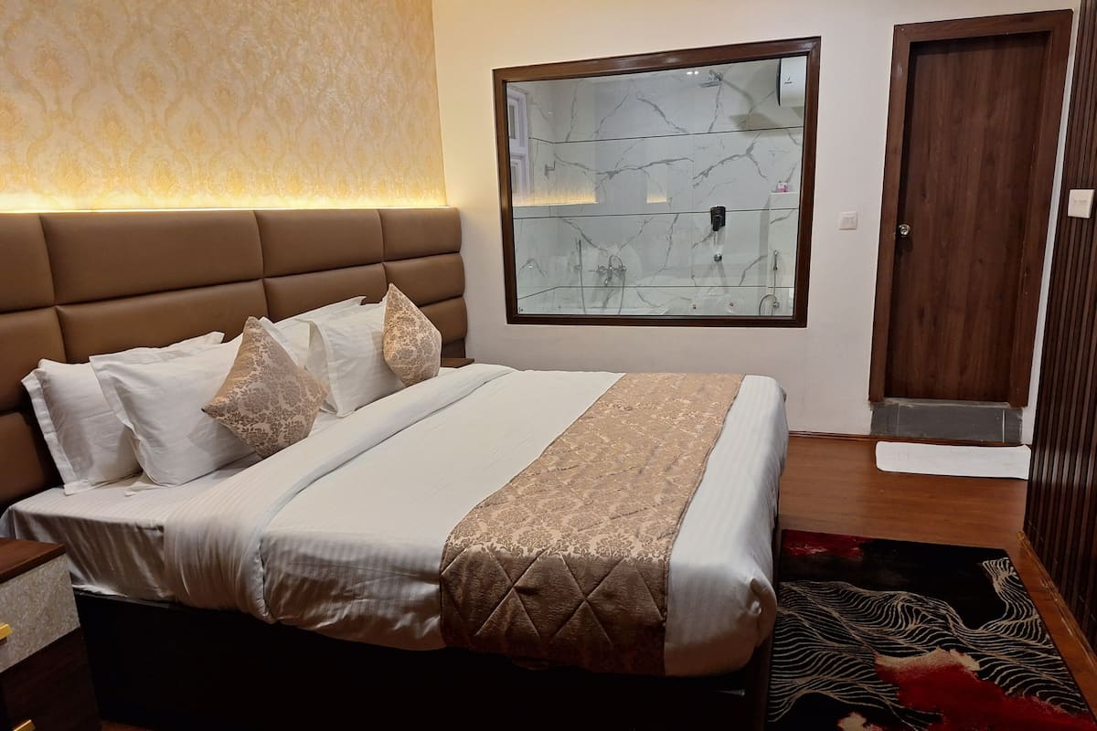A neatly made bed with a headboard, a bedside table, a large mirror, and a wooden door.