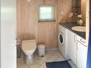 A compact bathroom with a toilet, washing machine, and sink.