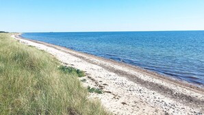 A beach with a clear sky, a sandy shore, and a calm sea. - 4 Star Holiday Home in Rodby (Rodby)