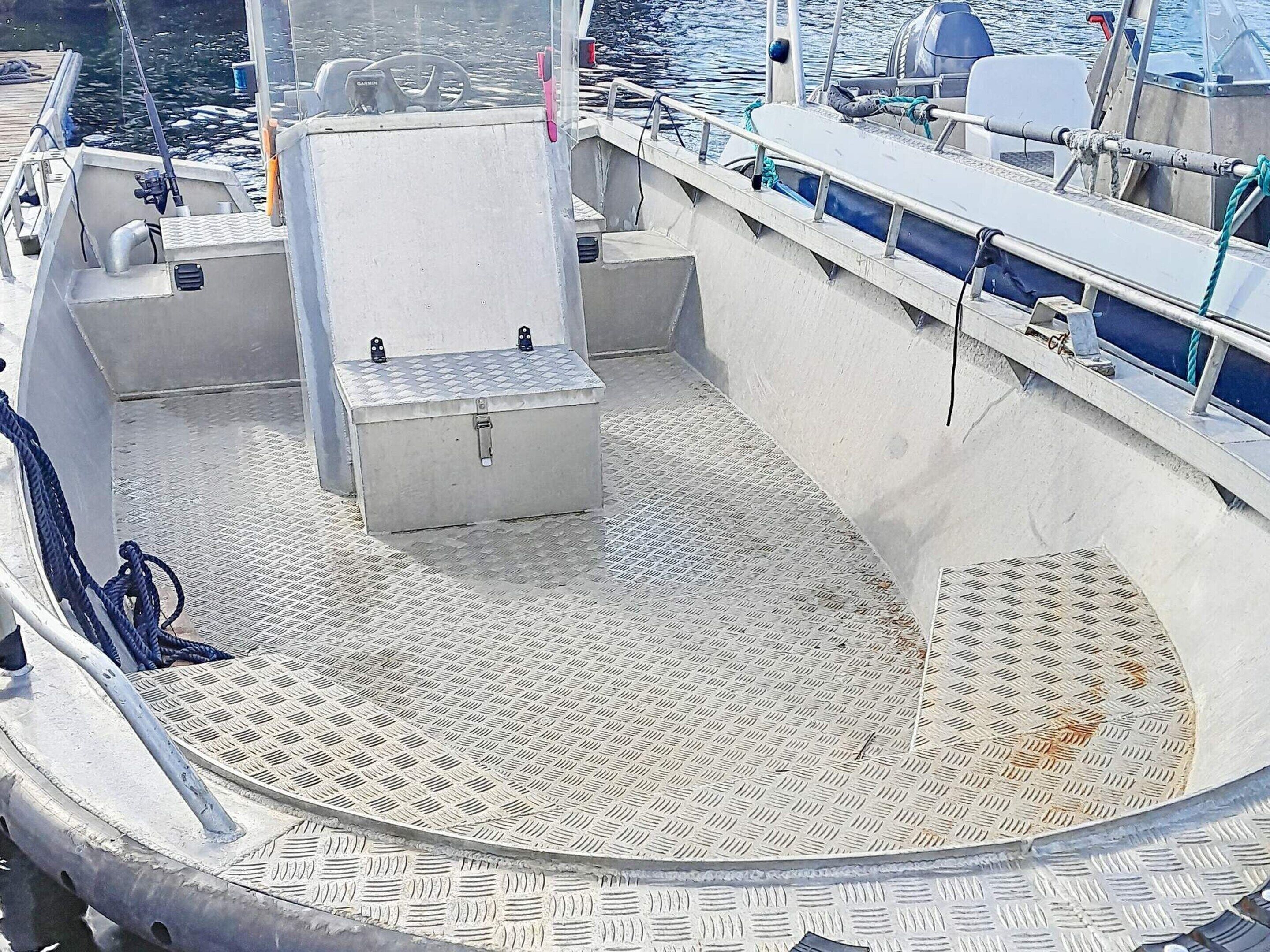 A boat deck with a metal floor, a white storage box, and a blue rope.