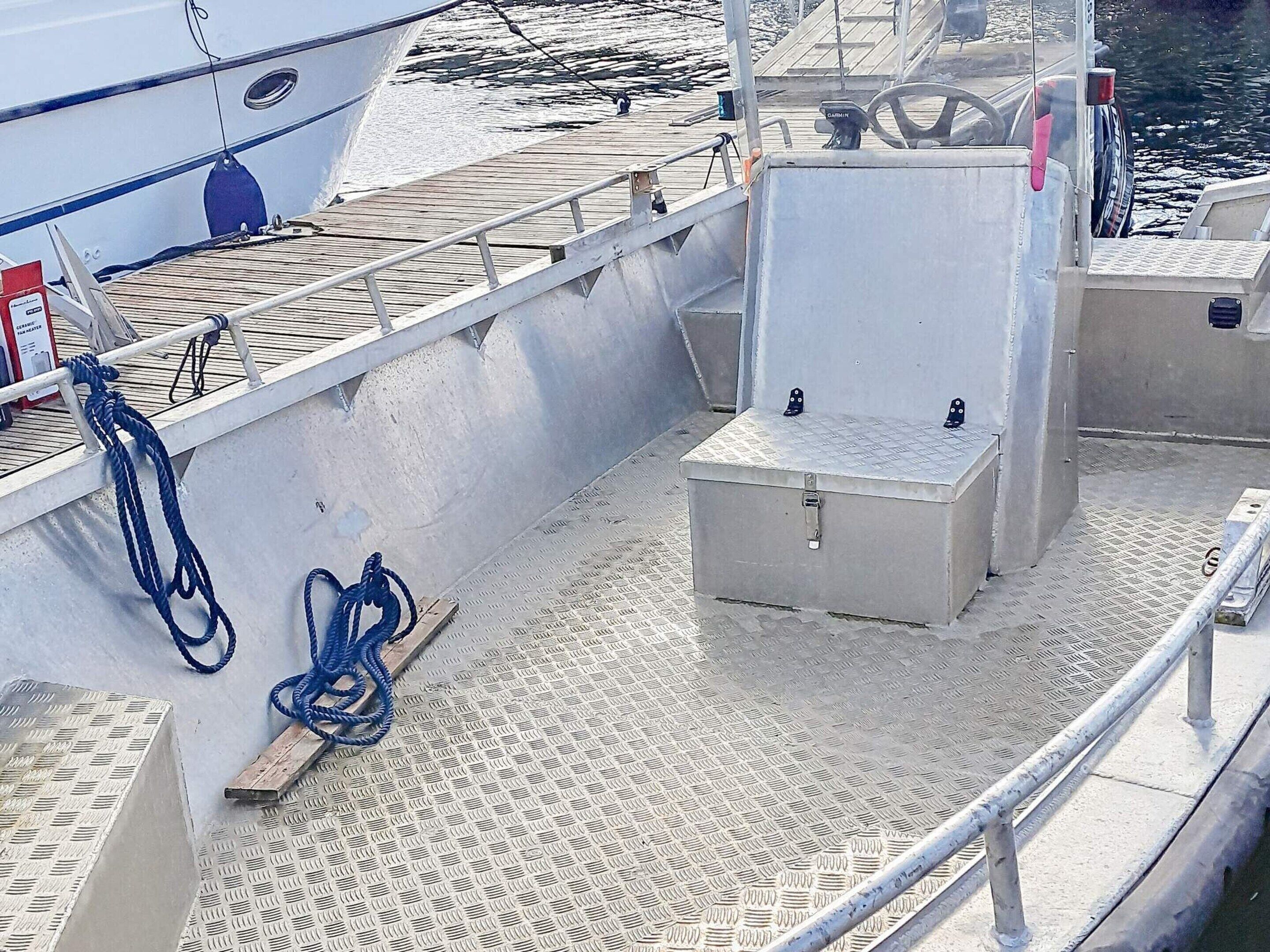 A boat deck with a metal railing, a lifebuoy, and a toolbox.