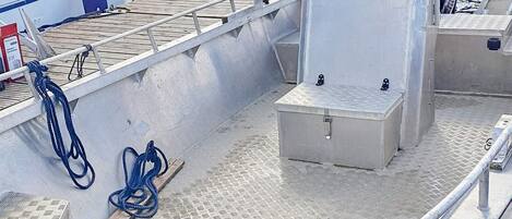 A boat deck with a metal railing, a lifebuoy, and a toolbox.