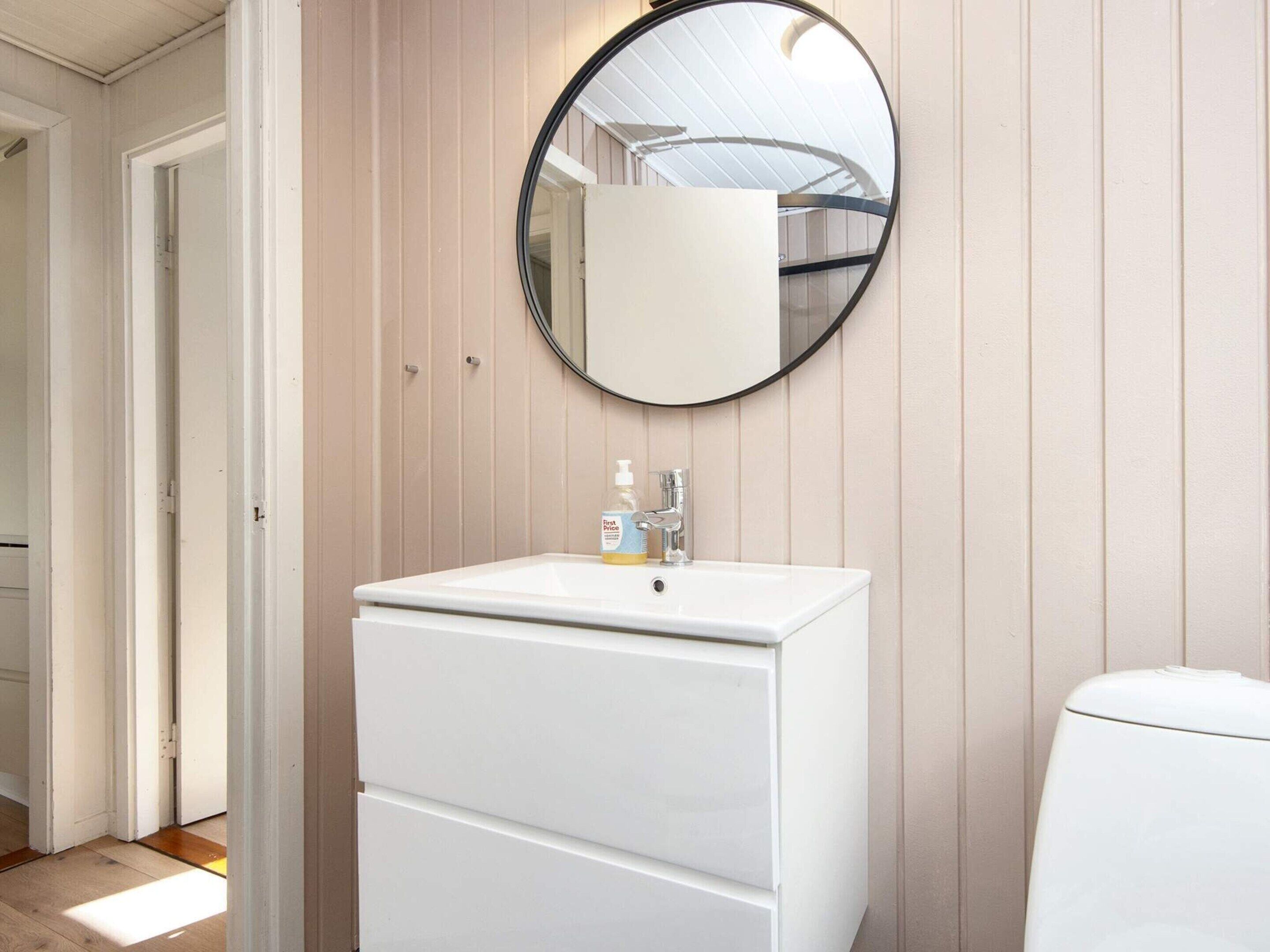 Une salle de bain avec un lavabo blanc, un miroir et des toilettes.