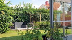 Een tuin met een pergola, potplanten en een gazon.