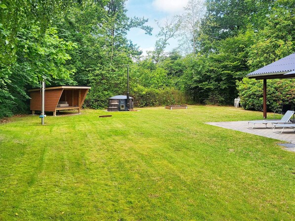 A well-maintained grassy backyard with a wooden structure, a small shed, and a covered seating area.