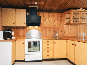A kitchen with wooden cabinets, a stainless steel oven, a microwave, and a sink.