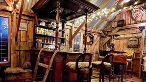 Un intérieur rustique en bois, avec un coin bar, des chaises en bois et une grande structure circulaire.