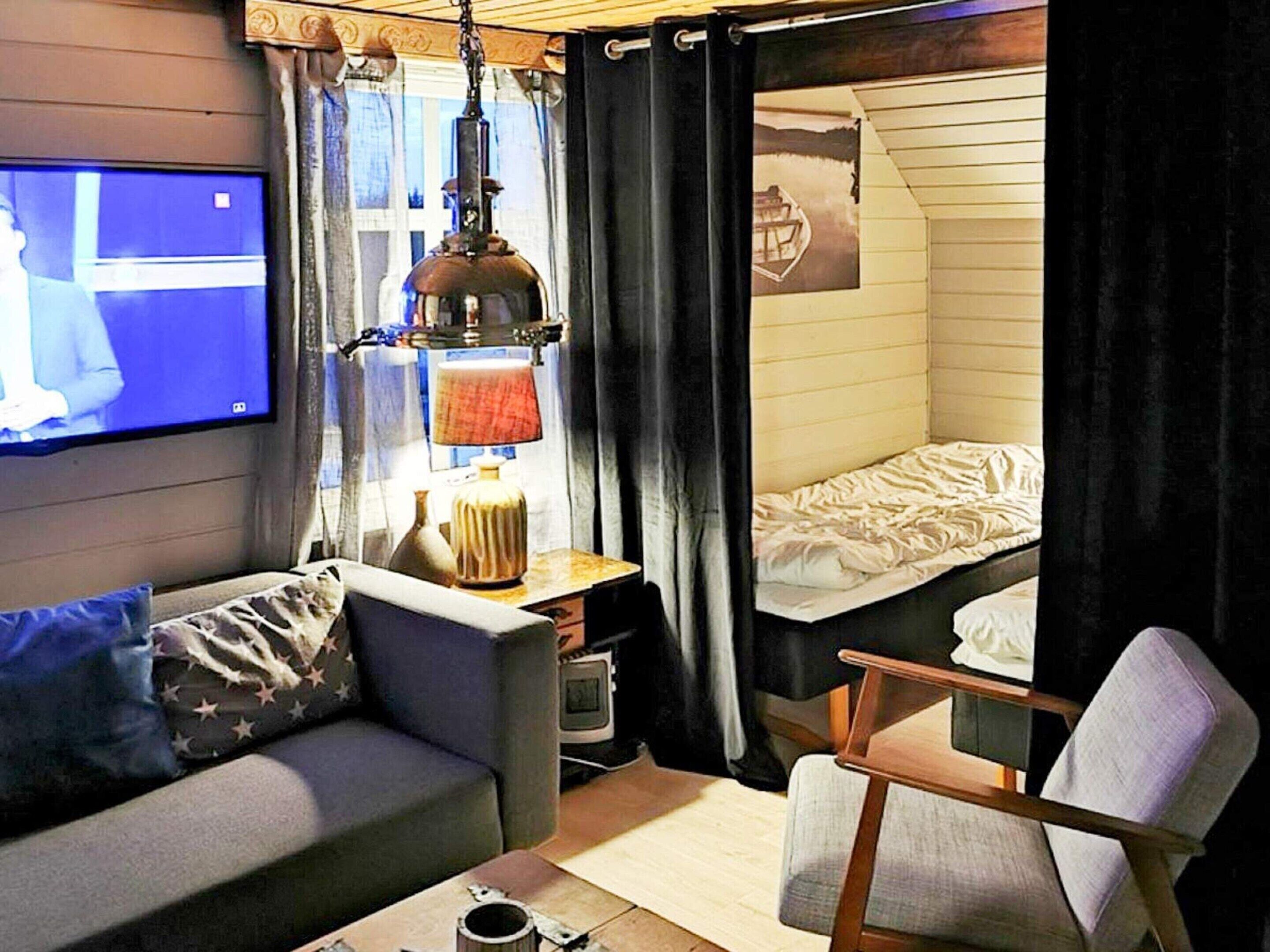 A compact room with a television, a lamp, a sofa, a chair, and a bunk bed.