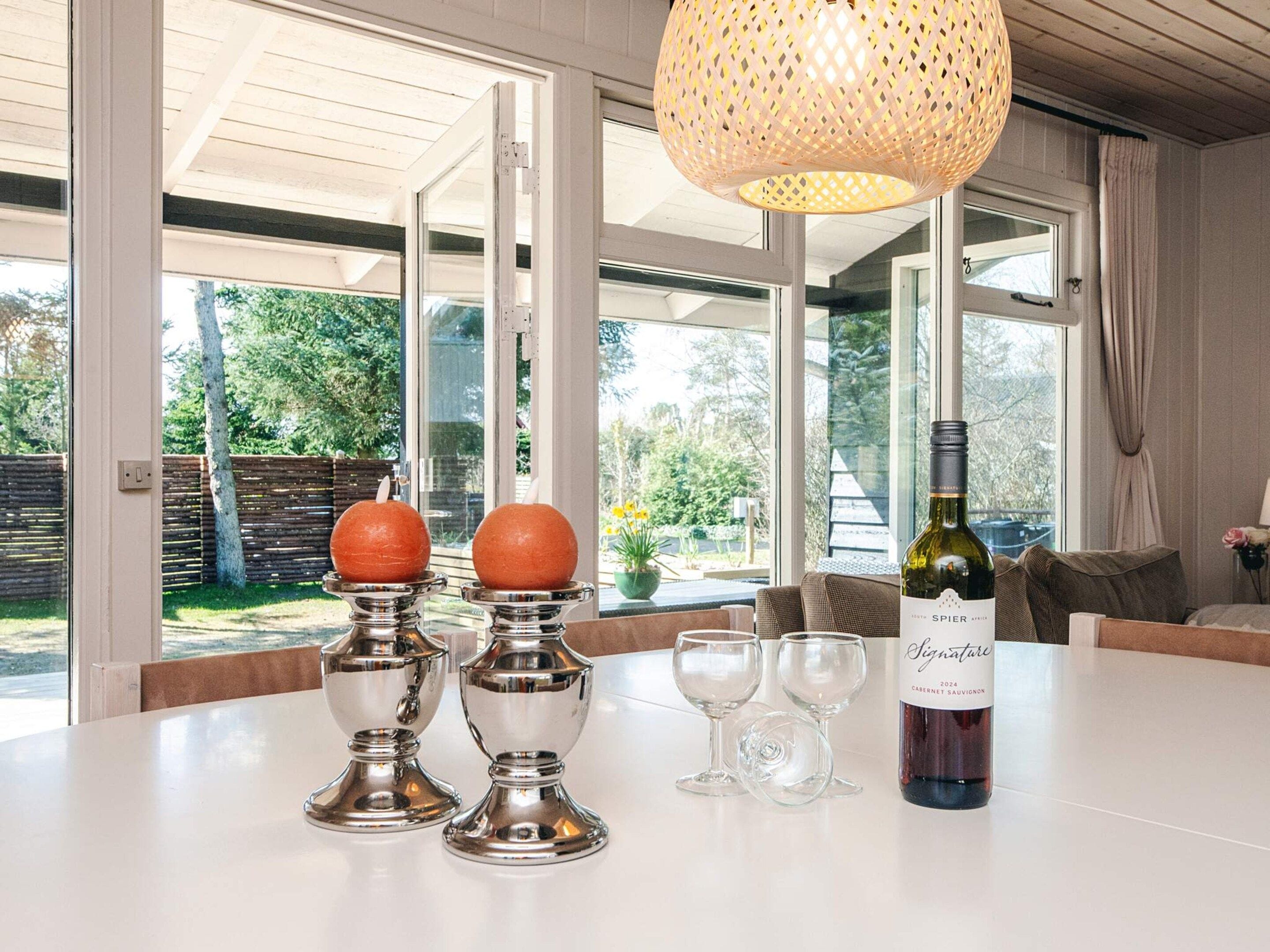 Une table à manger avec une bouteille de vin, deux chandeliers et deux verres à vin.
