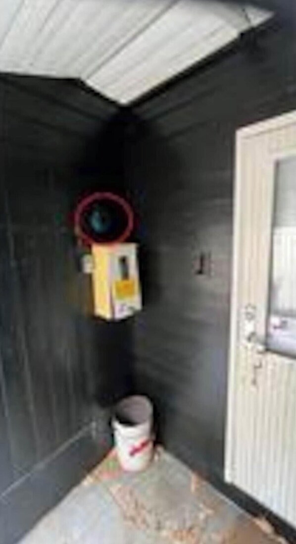 A room with dark walls, a white door, and a red circular object on the wall.