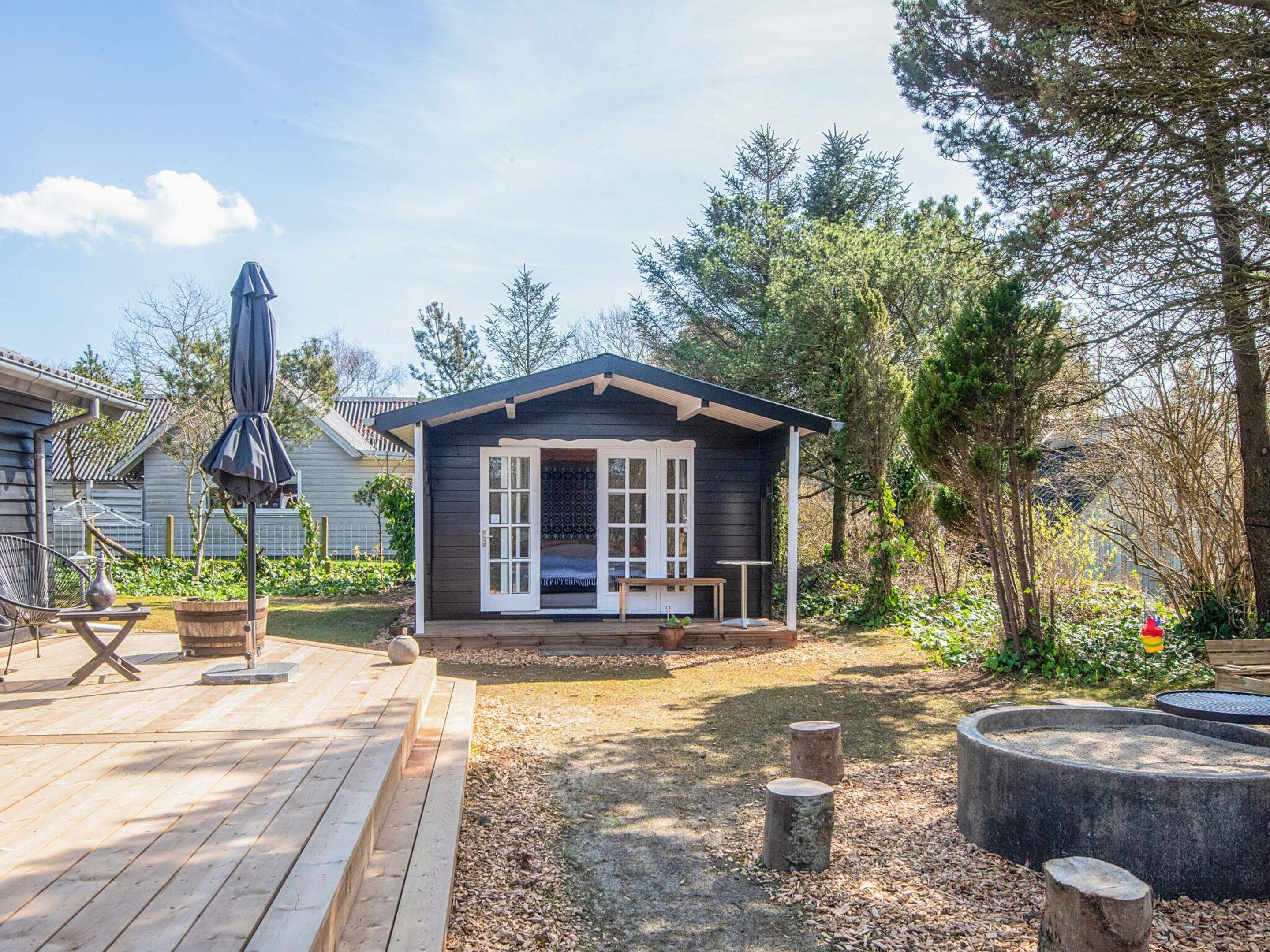 Una piccola baita con una veranda, un barbecue e un focolare nel giardino.