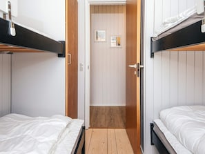 Una habitación con literas, piso de madera y una puerta que da a otra estancia.