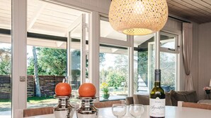 A dining table with a bottle of wine, two candlesticks with oranges, and three wine glasses.