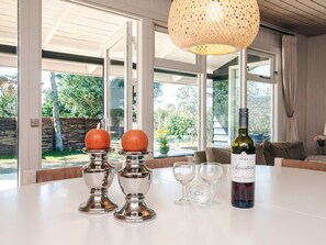 Una mesa de comedor con una botella de vino, dos candelabros con naranjas y tres copas de vino.