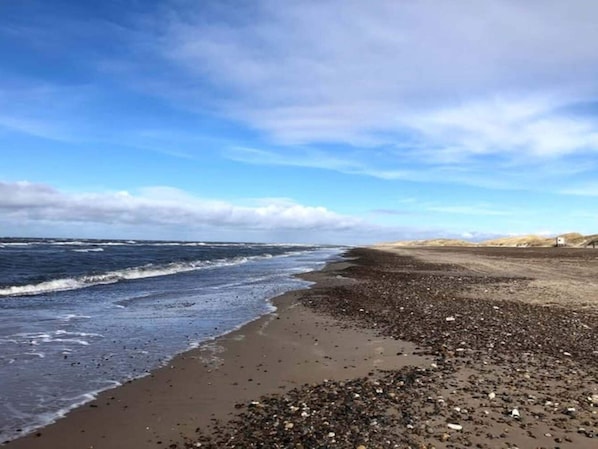 A beach with a rocky shoreline and waves crashing onto the sand.