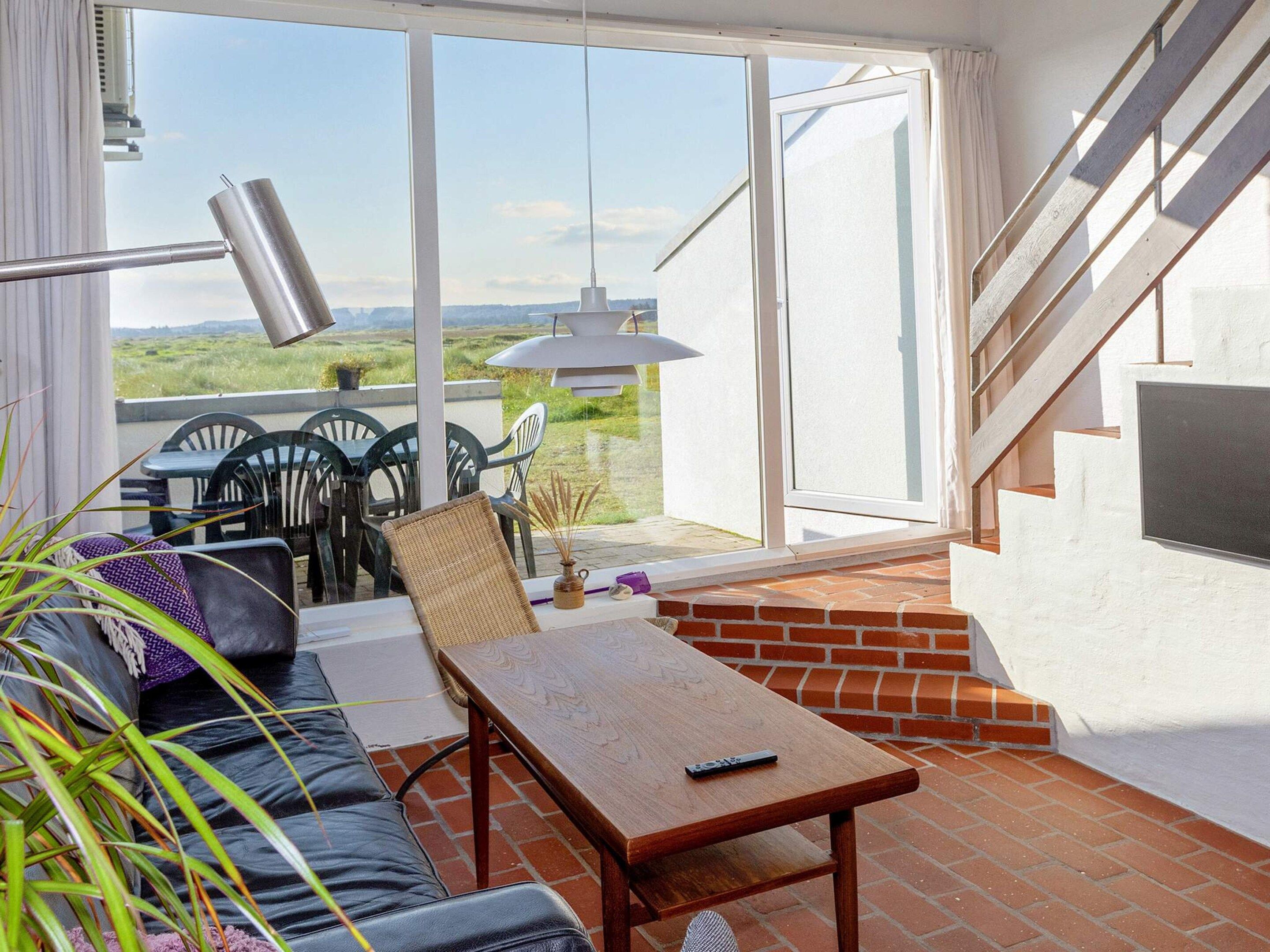 En balkong med en soffa, ett bord, stolar och utsikt över landskapet.