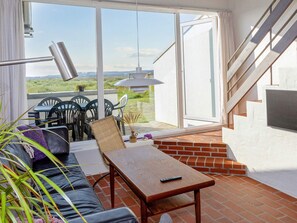 A balcony with a sofa, table, chairs, and a view of the landscape.