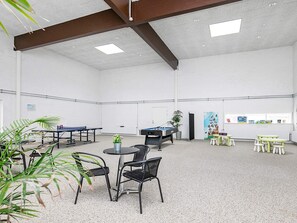 A spacious indoor area with tables and chairs, a pool table, and a ping pong table.