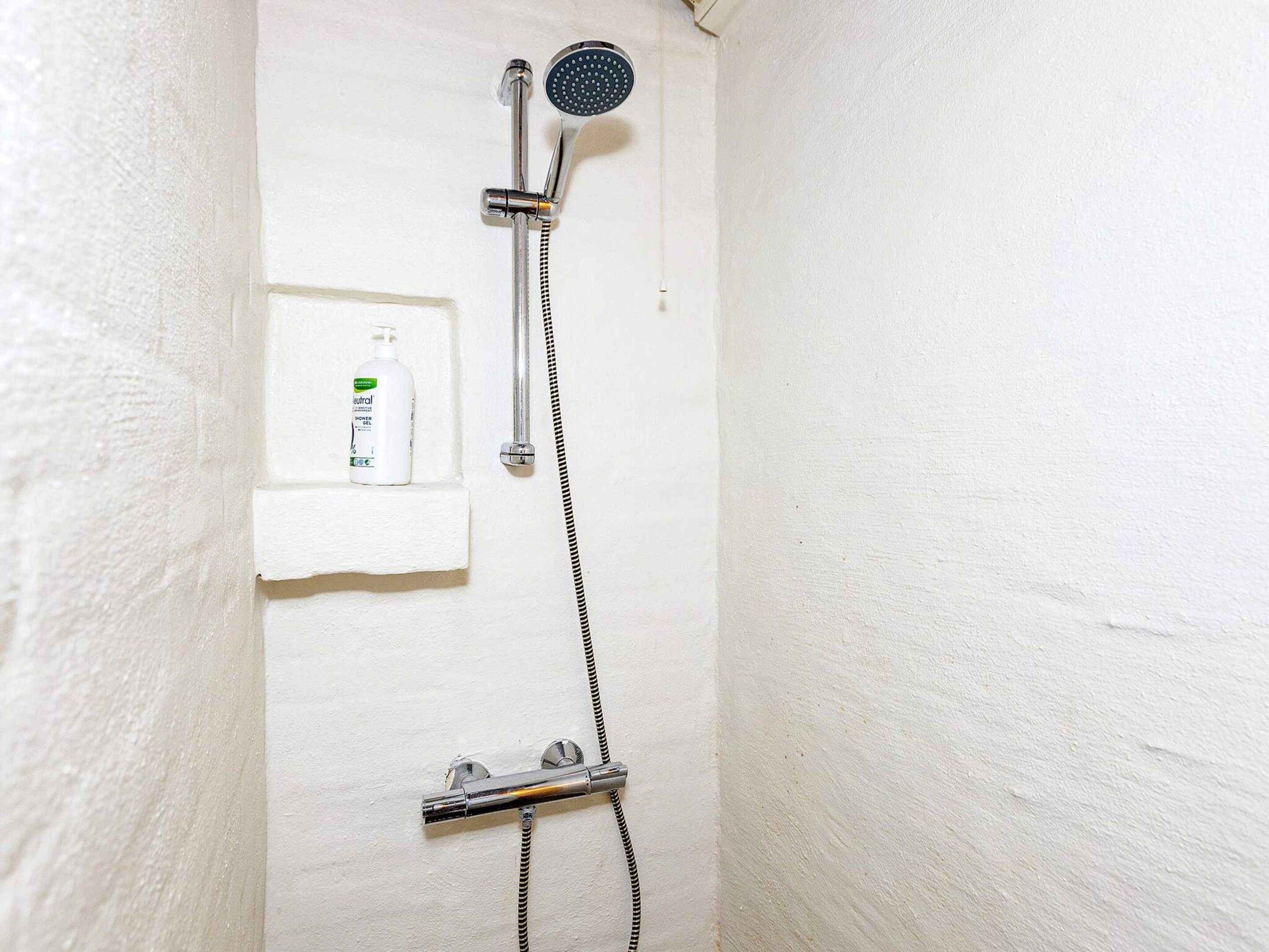 Eine Dusche mit Handbrause und Armaturen an der Wand.