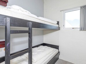 A bunk bed room with a window and a door.