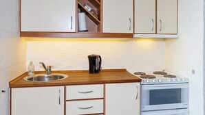A compact kitchen with a sink, stove, and cabinets.