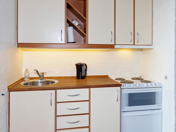 Una cocina compacta con lavamanos, estufa y armarios.