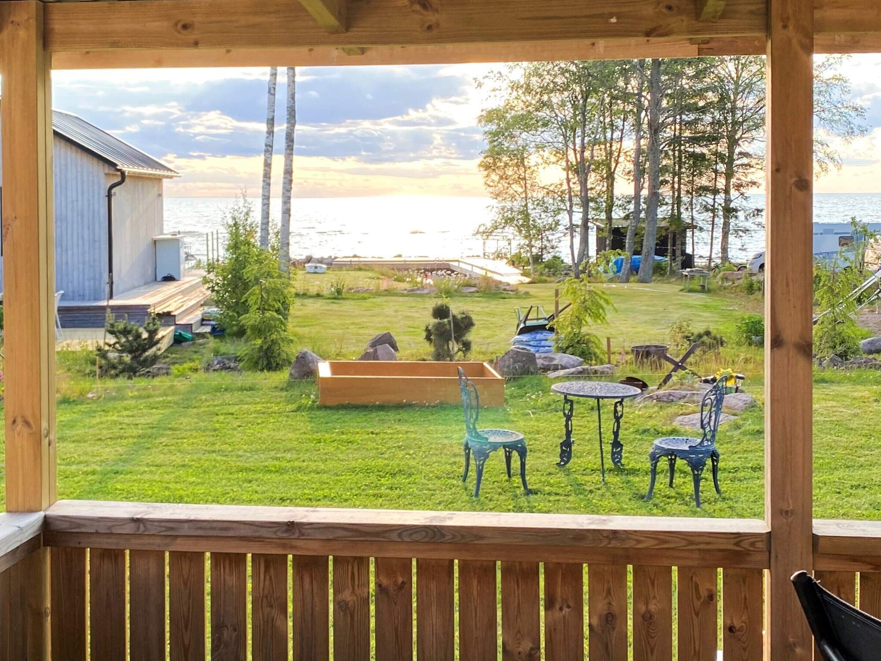 A wooden deck with a view of a grassy yard, a wooden bench, and a metal table.