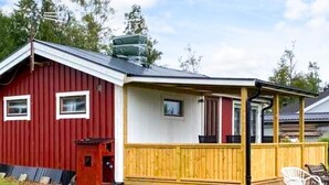 Une grange rouge avec un porche en bois et une zone abritée.