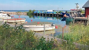 Un port de plaisance avec plusieurs bateaux amarrés, une jetée et un bâtiment rouge en arrière-plan.