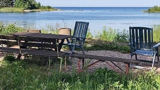Un cadre idyllique au bord du lac, avec une table et des chaises, entouré de verdure et offrant une vue sur l’eau.