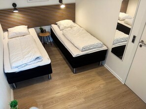 Habitación de hotel con dos camas, una mesita redonda con una planta y un espejo en la puerta.