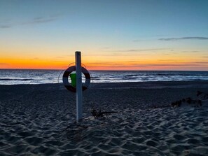 A lifebuoy attached to a pole on a beach at sunset. - 6 Person Holiday Home in Ringkobing (Ringkobing)