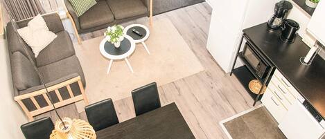 A modern interior with a sofa, two round tables, a dining table, and a kitchen area.