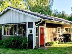 A single-story house with a porch, a red door, and a small attached garage. - 7 Person Holiday Home in Bergkvara (Bergkvara)