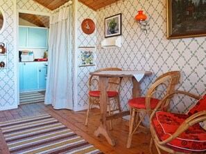 A cozy room with a dining table, wicker chairs, a kitchen in the background, and a patterned wallpaper. - 7 Person Holiday Home in Bergkvara (Bergkvara)