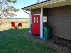 A building with a red door, a small porch area, and two red chairs outside.