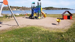 Une aire de jeux avec un toboggan et des structures d’escalade, située près d’un lac.