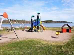 Un parque infantil con tobogán y estructuras para escalar cerca de un lago.