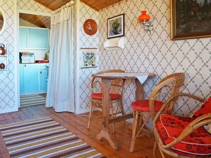 A cozy room with a dining table, wicker chairs, a kitchen in the background, and patterned wallpaper. - 7 Person Holiday Home in Bergkvara (Bergkvara)