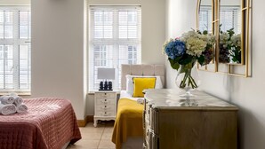 A bedroom with a bed, a nightstand, a dresser, a mirror, and a window with blinds.
