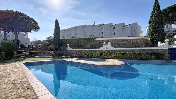 Une piscine bordée de pierres, un mur en pierre et un bâtiment en arrière-plan.