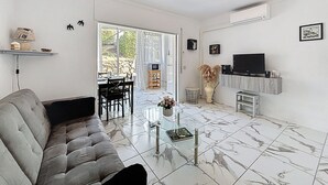 Un salon moderne avec un canapé gris, une table basse en verre et un téléviseur posé sur un meuble en bois.