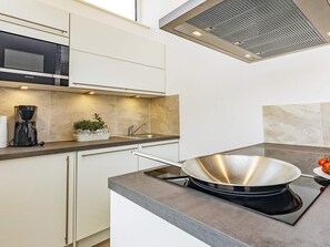 A modern kitchen with a built-in microwave, a coffee maker, a sink, and a stove. - 5 Star Holiday Home in Wendtorf (Wendtorf)