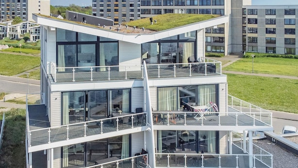 A modern multi-story building with glass balconies and outdoor seating areas.
