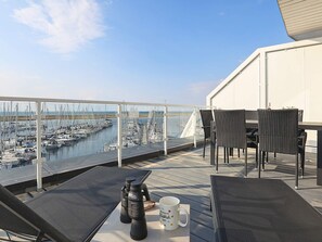 A terrace with a view of a marina, furnished with chairs and a table, binoculars, and a mug. - 5 Star Holiday Home in Wendtorf (Wendtorf)