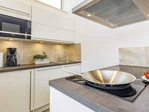 Una cocina moderna con microondas integrado, cafetera y estufa.