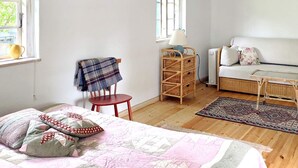 A bedroom with a bed, a chair, a sofa, a table, and a lamp. - 5 Person Holiday Home in Bogo By (Bogø By)