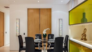 Een moderne eetruimte met een houten deur, zwarte stoelen en een glazen tafel.